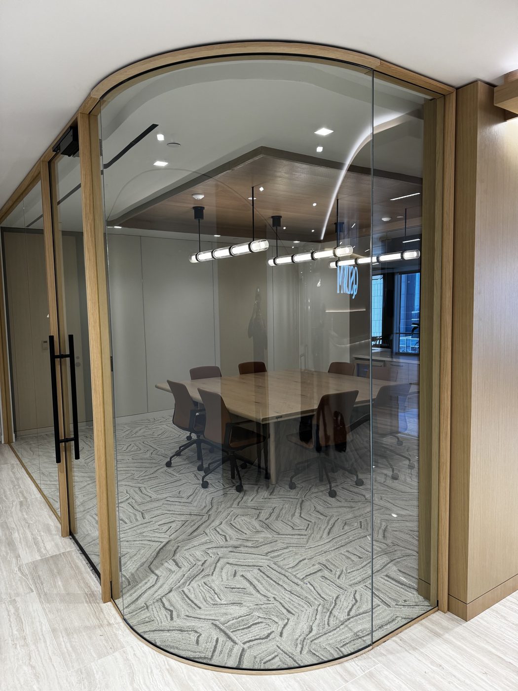Curved glass meeting room with bronze frame